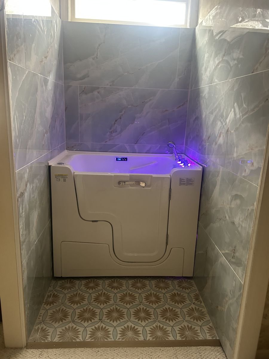 Walk-in tub with marble tile surround and LED lighting